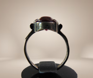 Antieke zilveren ring met patina rode glas steen breuk beige achtergrond