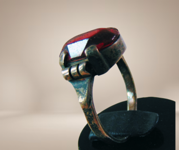 Antieke zilveren ring met patina rode glas steen breuk beige achtergrond 1