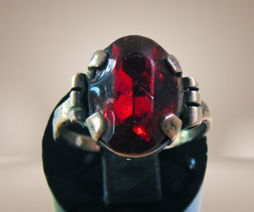 Antieke zilveren ring met patina rode glas steen breuk beige achtergrond 2