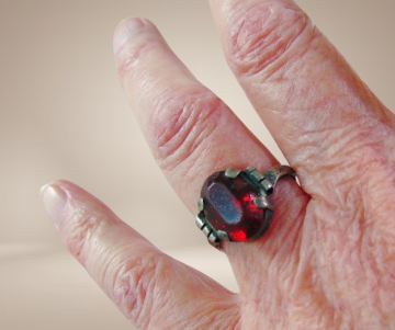 Antieke zilveren ring met patina rode glas steen breuk beige achtergrond 3