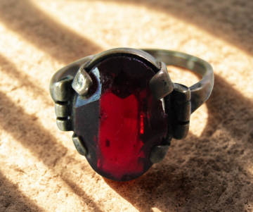 Antieke zilveren ring met patina rode glas steen breuk beige achtergrond 6