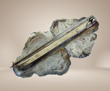 Antieke zilveren sierlijke bijbelslot broche beige achtergrond 2