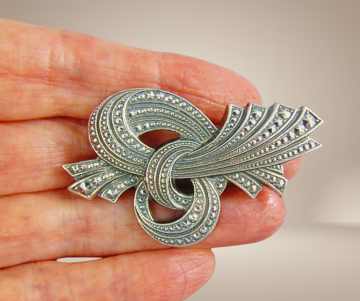 Art nouveau stijl  broches zilver strik knoop puntjes beige achtergrond