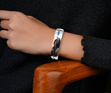 Brede navajo hopi zilver overlay roadrunner armband op arm hout stoel