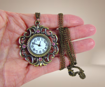 Brons kleur vintage antiekstijl horloge hanger ketting roze strass beige achtergrond