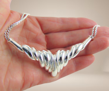 Grosse punt ketting zilver op hand beige achtergrond