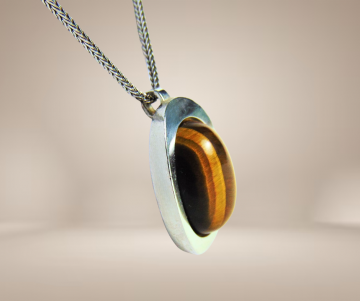 Grote teka theodor klotz modernist zilver tijgeroog hanger ketting beige achtergrond