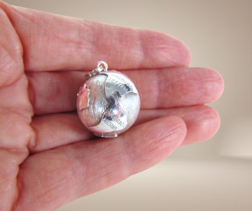 Grote zilveren wereldbol hanger latijns beige achtergrond