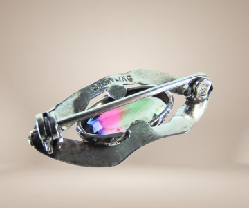 Kleine sterling zilveren broche regenboog steen beige achtergrond