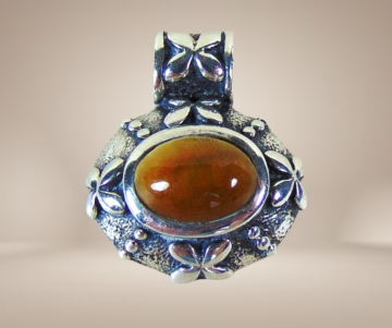 Kleine zilveren ovale thai hanger met bloempjes bruingele jade beige achtergrond