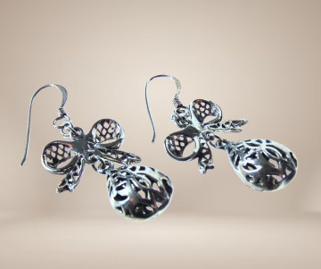 Lange zware zilveren filigraan strik druppel oorbellen beige achtergrond