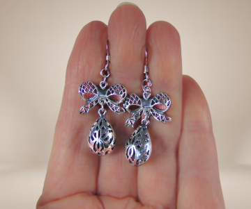 Lange zware zilveren filigraan strik druppel oorbellen beige achtergrond 2