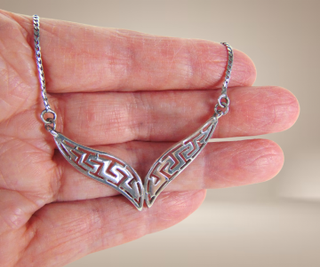 Meander zilveren middenstuk ketting beige achtergrond