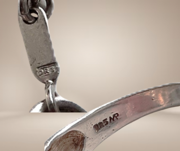 Modernist mat glans zilver v golf ketting en ring merk beige achtergrond