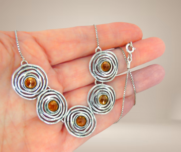 Modernistisch zilveren bib cirkels citrien ketting beige achtergrond