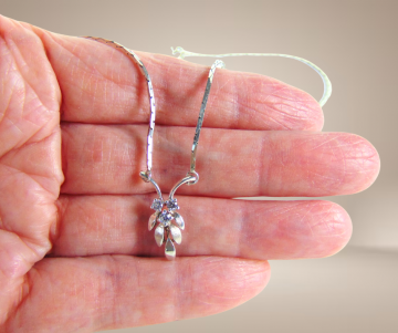 Sierlijke ketting met dainty blaadjes hanger kristal zilver beige achtergrond