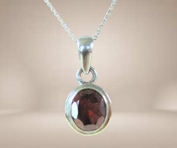 Strak zilveren ovale granaat hanger aan ketting beige achtergrond