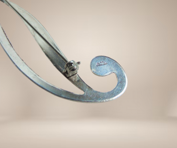 Strakke modernist  am zilver slee krul broche gravure beige achtergrond