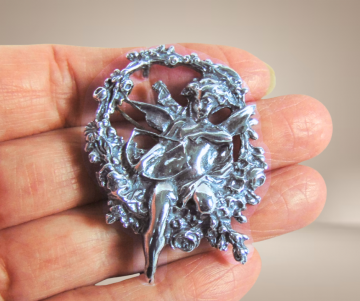 Timeless classics zilveren art nouveau cupido broche beige achtergrond