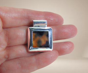 Vierkante zilveren hanger tijger kauri schelp beige achtergrond