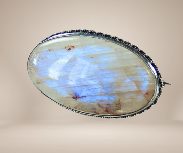 Vuur maansteen ovale zilveren broche beige achtergrond