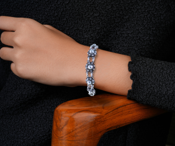 Zeeuwse knoop knop zilveren armband antiek op arm hout stoel