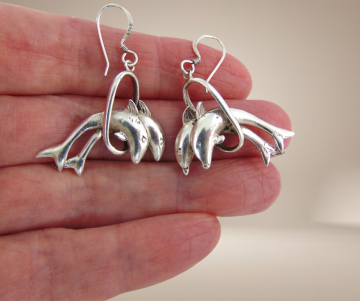 Zilveren oorbellen  dolfijnen door hoepel beige achtergrond